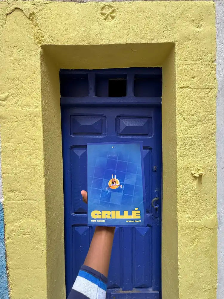 Cahier Grillé niveau doux affiché sur porte bleue, façade jaune, jeu mots fléchés nouvelle génération