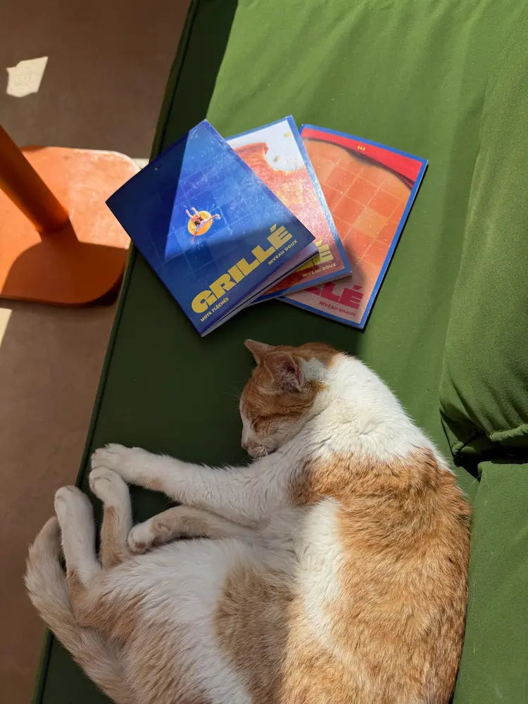 Chat marron et blanc jouant avec les cahiers de mots fléchés Grillé sur un tapis vert