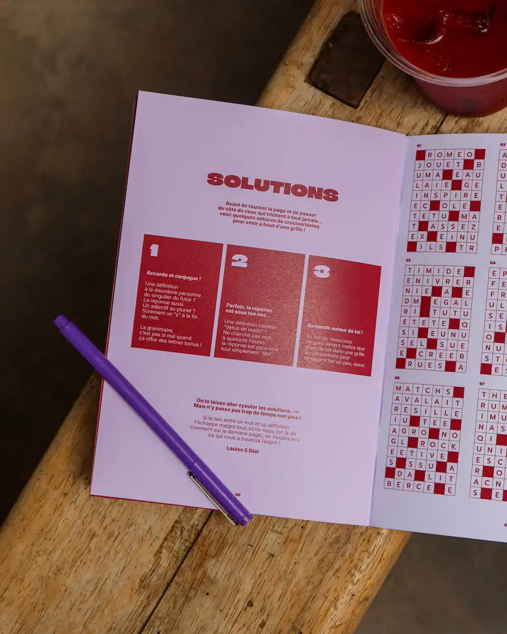 Cahier Grillé ouvert sur la page solutions avec grilles de mots fléchés thème amour et stylo violet